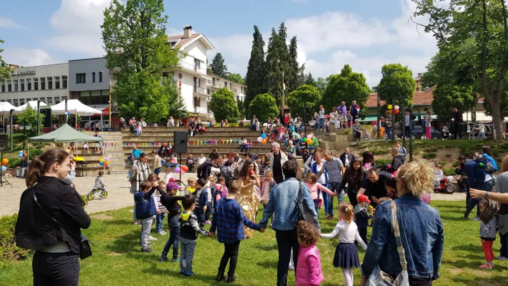 Деца и родители играят хоро в парк по време на празник