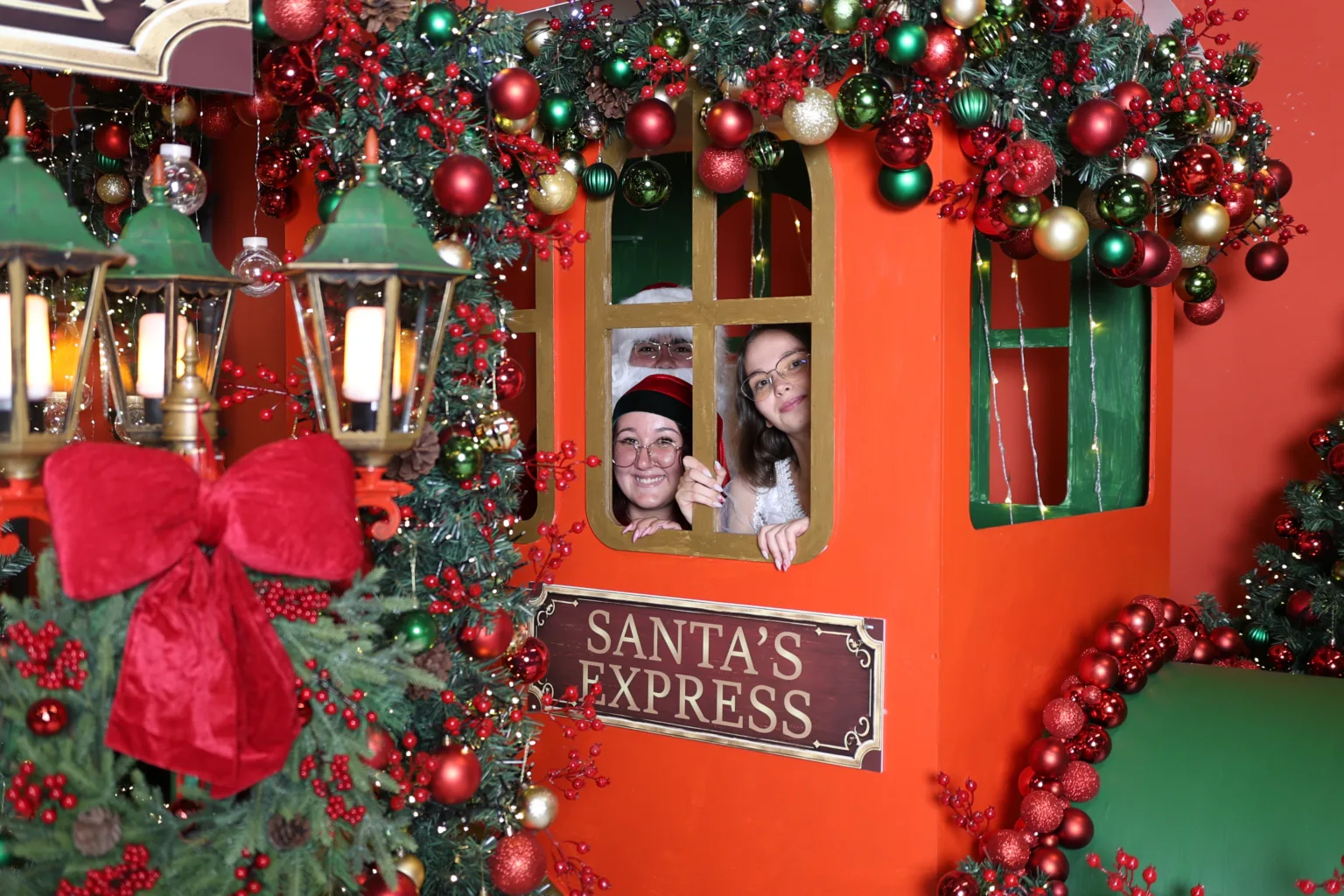 Две момичета надничат от прозореца на коледния влак Santa’s Express